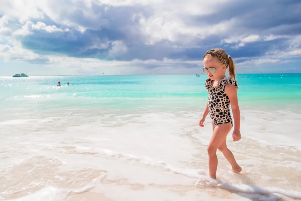 Adorable niña se divierten en aguas poco profundas en la playa blanca —  Fotos de Stock