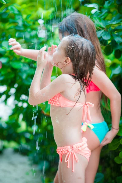 Adorable little girls under beach shower on tropical beach — Stock Photo, Image