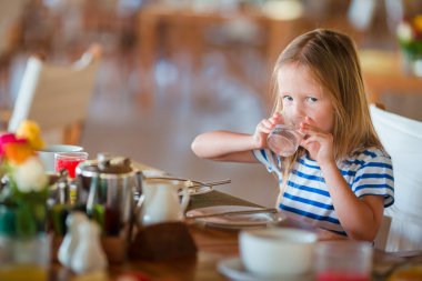 Küçük bir çocuk açık kafede kahvaltı. Sevimli kız kahvaltınızın tadını taze karpuz suyu içme.
