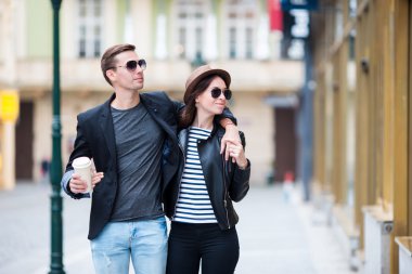 Romantik Çift birlikte Avrupa'da yürüme. Mutlu aşıklar Cityscape ünlü simge ile zevk. Sıcak kahve ve seyahat Prag şapkalı kadın şık kentsel genç adam