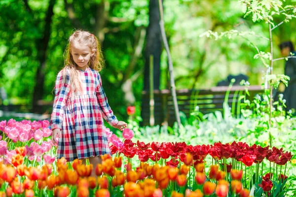 Niña adorable en el jardín de tulipanes florecientes. Exposición de diferentes variedades de tulipanes en el parque al aire libre —  Fotos de Stock