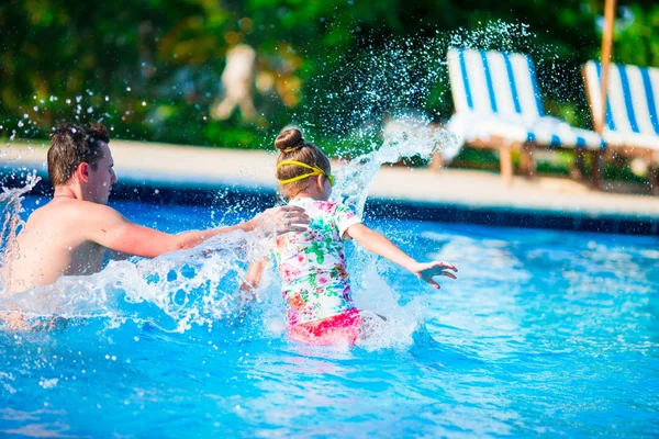 Happy family having fun together in outdoors swimming pool — Stock Photo, Image