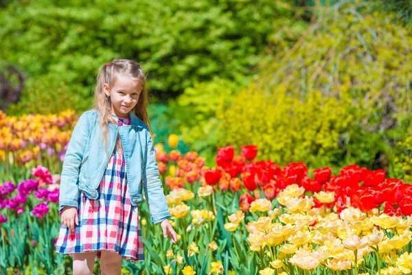 Niña adorable en el jardín de tulipanes florecientes. Cálido día de primavera al aire libre —  Fotos de Stock