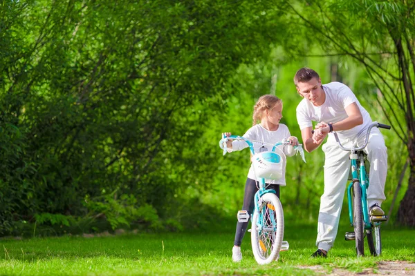 Giovane padre e bambina in bicicletta nel giorno caldo estivo. Giovane famiglia attiva in bicicletta — Foto Stock