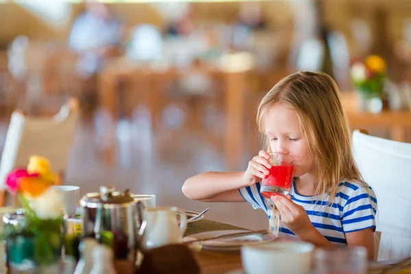 Kleines Kind frühstückt im Café im Freien. entzückendes Mädchen trinkt frischen Wassermelonensaft und genießt das Frühstück. — Stockfoto