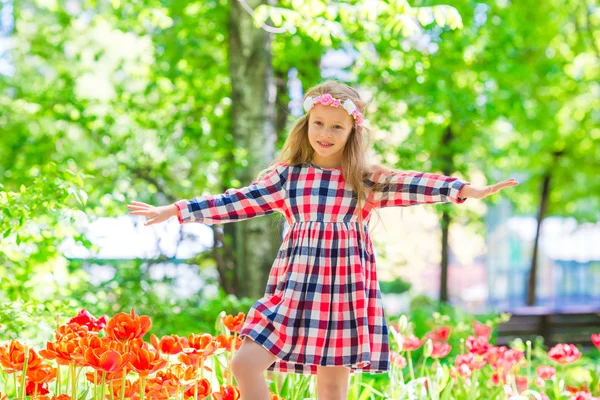 Niña adorable en el jardín de tulipanes florecientes. Exposición de diferentes variedades de tulipanes en el parque al aire libre —  Fotos de Stock