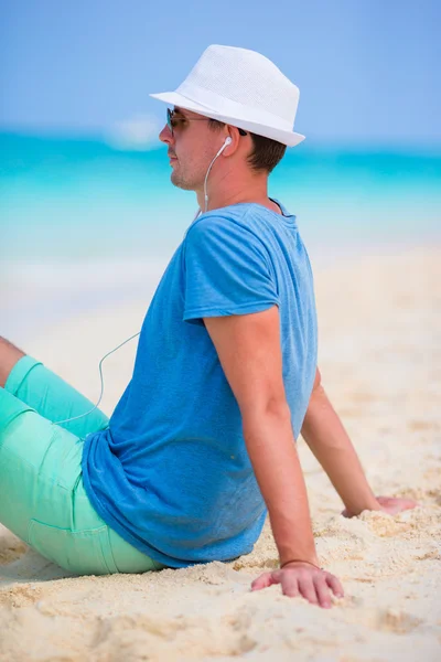 Glad ung man njuter av musiken på vit sandstrand — Stockfoto