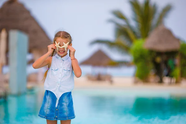 Yaz tatilinde kumsalda deniz yıldızı olan sevimli küçük bir kız. — Stok fotoğraf
