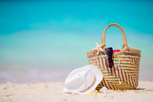 Plážové doplňky - slaměné tašky, bílý klobouk, hvězdice a černé brýle na pláži. Letní pláž koncept — Stock fotografie