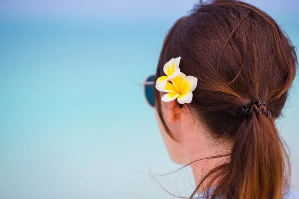 Giovane bella donna durante le vacanze al mare tropicale. Godetevi una vacanza suumer da solo sulla spiaggia in Africa con i fiori frangipani tra i capelli — Foto Stock