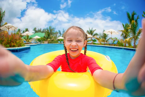 Little girl making selfie at inflatable rubber ring having fun in swimming pool — Stock Photo, Image