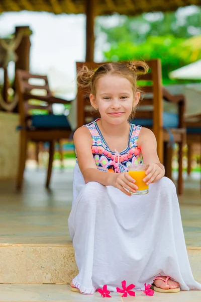 Bedårande liten flicka med apelsinjuice på uteservering — Stockfoto