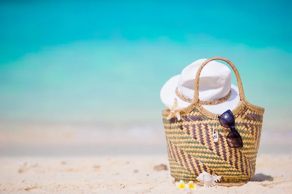 Acessórios de praia - saco de palha, chapéu branco e óculos de sol pretos na praia . — Fotografia de Stock