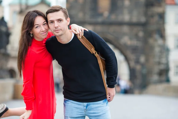 幸福的夫妇在布拉格的查尔斯桥上行走。微笑爱好者享受的景观，如著名的地标. — 图库照片