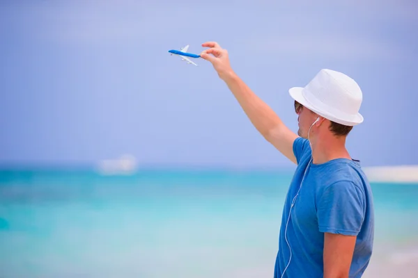 Молодий чоловік з іграшковим літаком насолоджується музикою на пляжній відпустці. Щасливий хлопчик насолоджується пляжем і теплою погодою під час прогулянки уздовж океану — стокове фото