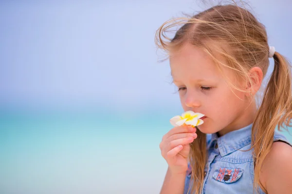 Portræt af sød lille pige med blomst på stranden sommerferie - Stock-foto
