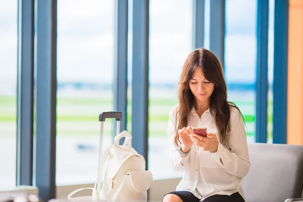 Kvinnliga passagerare vid en flygplatslounge väntar flyg flygplan. Siluett av kvinna med mobiltelefon i flygplatsen gå till landning — Stockfoto