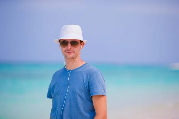 Joven disfrutando de la música en la playa de arena blanca. Turista feliz relajándose en vacaciones tropicales de verano . — Foto de Stock