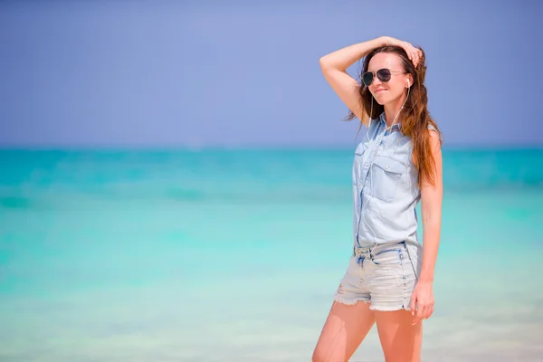 Молодая красивая женщина наслаждается музыкой на белом пляже — стоковое фото