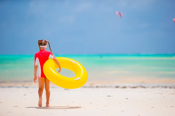 Rozkošná holčička s gumové nafukovací kruh během beach dovolenou. Děti baví na aktivní dovolenou v létě — Stock fotografie