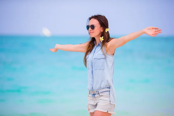 Hermosa chica durante las vacaciones en la playa tropical. Disfrute de vacaciones suumer solo en la playa de África con flores de frangipani en su cabello — Foto de Stock