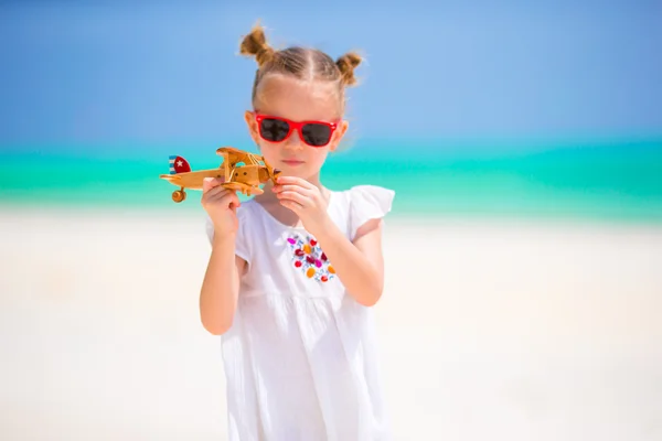 Ragazzina felice con aeroplano giocattolo in mano sulla spiaggia di sabbia bianca. Foto di viaggi pubblicitari, voli e compagnie aeree — Foto Stock