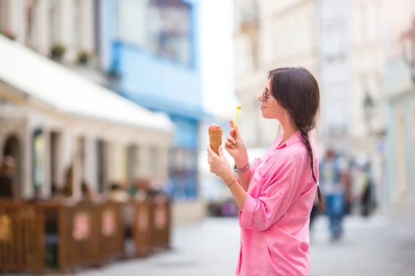 Young female model eating ice cream cone outdoors. Summer concept - woamn with sweet ice-cream at hot day — Stock Photo, Image