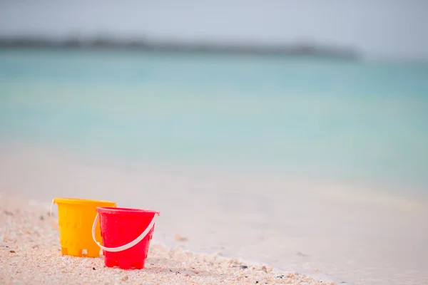 Juguetes de playa para niños en arena blanca. Cubos y cuchillas para niños en la playa de arena blanca después de juegos infantiles — Foto de Stock