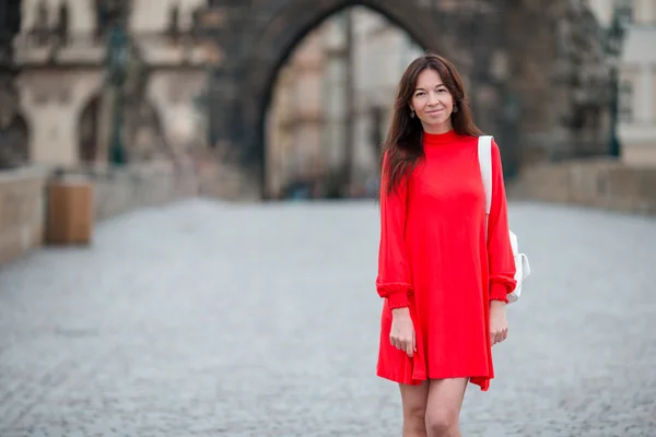 Mujer urbana joven feliz en la ciudad europea en el famoso puente. Turista caucásico caminando por las calles desiertas de Europa. Cálido verano por la mañana temprano en Praga, República Checa — Foto de Stock