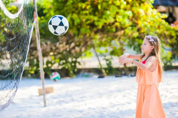 Little active girl playing voleyball on beach with ball. Sporty flid enjoying beach game outdoors — Stock Photo, Image