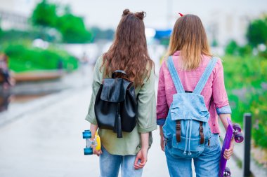 Gün batımı ışıkta açık havada kaykay ile iki hippi kız. Aktif sportif kadınlara paten parkta birlikte eğleniyor.