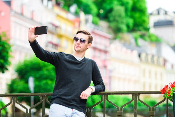 Toerist man het nemen van reisfoto's met smartphone op zomer vakantie. Jonge aantrekkelijke toerist het nemen van selfie foto met mobiele telefoon buitenshuis genieten van vakantie reisbestemming in het toerisme en — Stockfoto