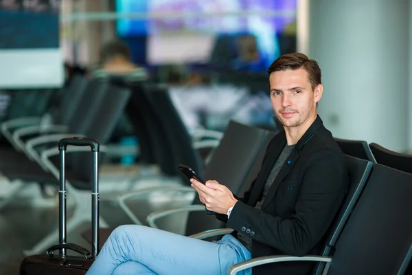 Αστική επιχείρηση άνθρωπος μιλάει στο έξυπνο τηλέφωνο που ταξιδεύουν στο εσωτερικό στο αεροδρόμιο. Φορώντας σακάκι κοστούμι casual νεαρός επιχειρηματίας. Όμορφος ανδρικό πρότυπο. Νεαρός άνδρας με κινητό τηλέφωνο στο αεροδρόμιο περιμένοντας — Φωτογραφία Αρχείου