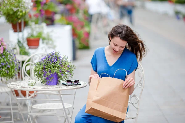 Mode fille heureuse avec des sacs après avoir fait du shopping en buvant du café dans le café openair. Vente, consumérisme et concept de personnes. fille caucasienne profiter de la journée chaude dans un café extérieur . — Photo