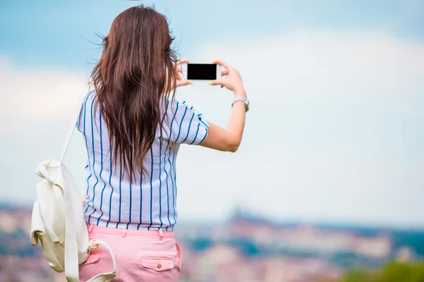 Mladá Kavkazský žena tím mobilních telefonů, Foto staré město z místa pozorování — Stock fotografie