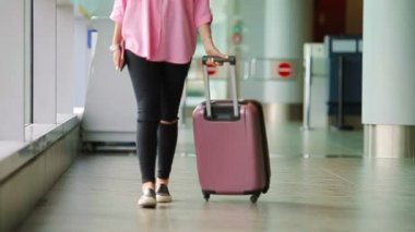 Pasaport ve biniş kartı ve pembe Bagaj bir Havaalanı lounge, closeup uçak yolcu. Uluslararası havaalanında kendi bavullarla yürüyen genç kadın.
