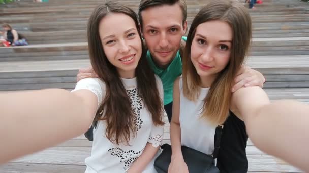 Skupina happy dospívajícího přátelé smát a užívat selfie na ulici. Tři přátelé sledování fotografování s tablet pc v parku — Stock video