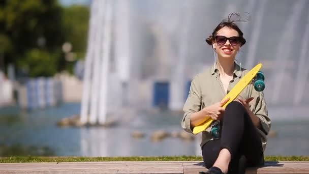 Молодая девушка развлекается со скейтбордом в парке. Портрет молодой позитивной женщины, развлекающейся и наслаждающейся теплой погодой . — стоковое видео