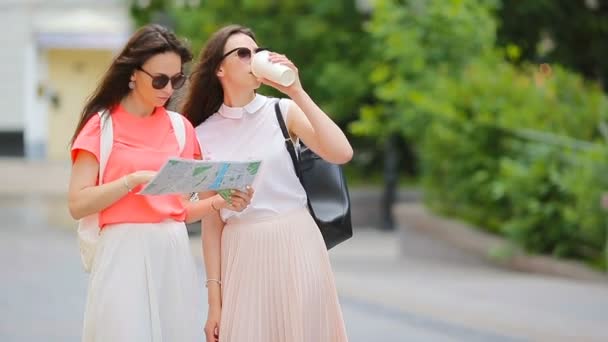 Jovens mulheres felizes com mapa andando ao longo da rua da cidade na Europa . — Vídeo de Stock