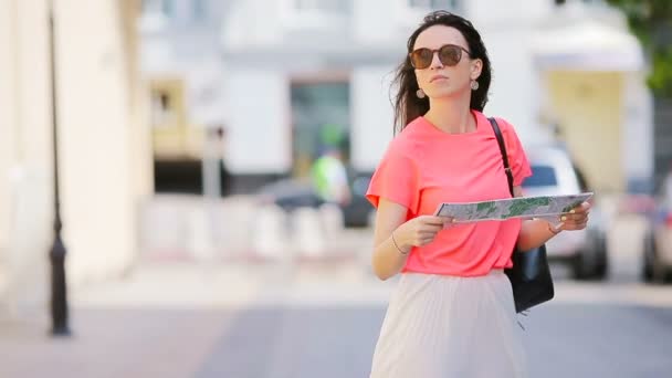 Happy young woman with map walking along city street in Europe ask help another caucasian girl — Stock Video