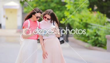 Mutlu genç kadınlar alışveriş torbaları şehir sokak yürüyüş ile. Satılık, tüketim ve insanlar kavramı.