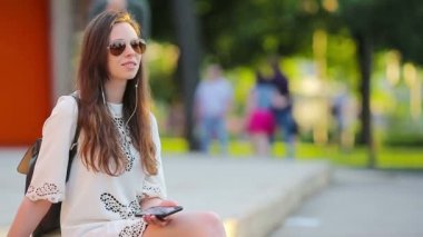 Young beautiful girl enjoy listening music and dancing outdoors. Beautiful hipster woman using a smart phone to listen her favourite songs