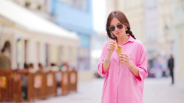 Young female model eating ice cream cone outdoors. Summer concept - woman with sweet ice-cream at hot day