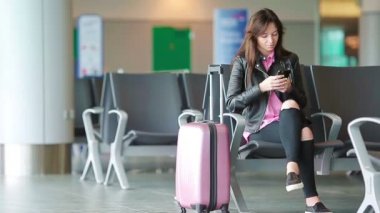Havayolu yolcu kız bir havaalanı salonunda uçuş uçağı bekliyor. Bekleme odasında akıllı telefonu olan beyaz kadın