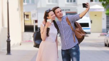 Mutlu arkadaşlar birlikte yürüyor ve Avrupa'da selfie çekiyorlar. Beyaz adam ve kız ünlü simgeleri ile şehir manzarası zevk.