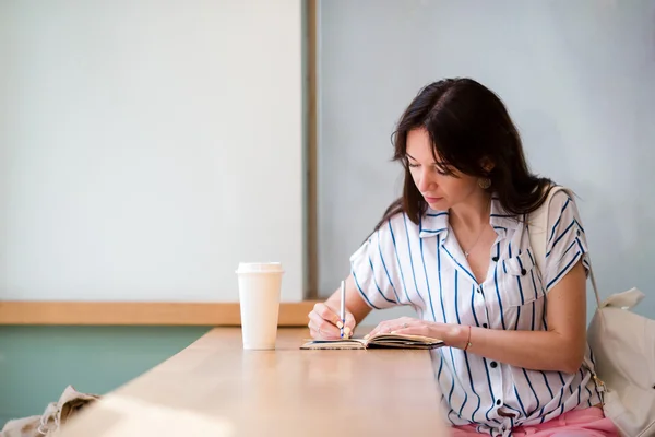 Портрет молодой красивой женщины, сидящей в кафе на открытом воздухе и пьющей кофе — стоковое фото