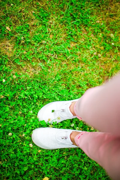 Primo piano di gambe femminili in scarpe da ginnastica sull'erba all'aperto nel parco . — Foto Stock