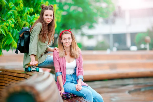 Två glada tjejer med skateboards utomhus. Aktiva sportiga kvinnor som har roligt tillsammans i Skate Park. — Stockfoto