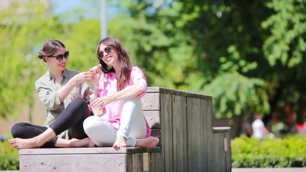 Счастливые молодые городские девушки слушают музыку в парке под открытым небом. Кавказские туристы веселятся на открытом воздухе — стоковое видео