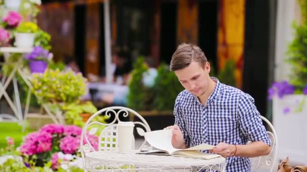 Kaukasischer junger europäischer Mann in einem Café im Freien. Porträt attraktiver junger Touristen beim Abendessen. — Stockvideo